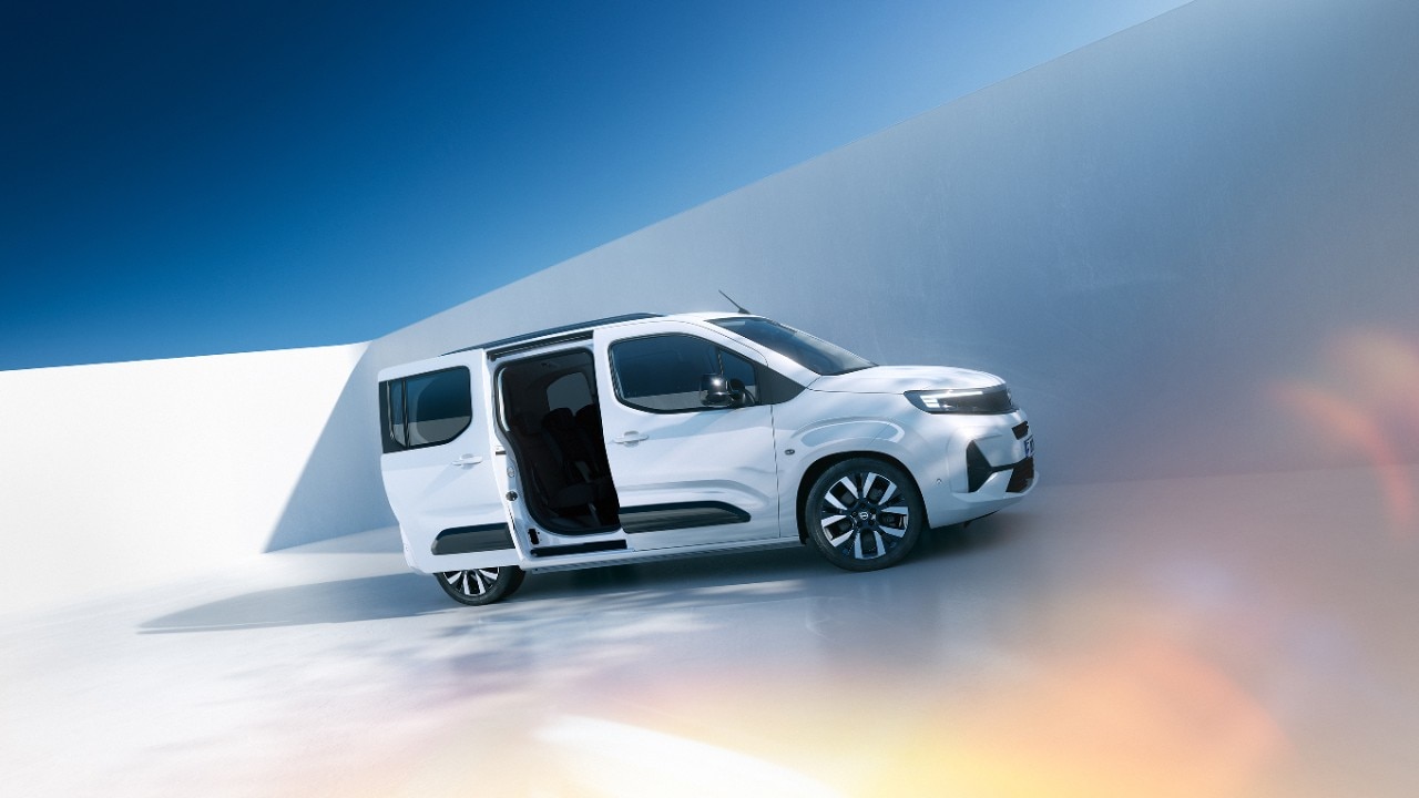 Pogled s strani na bel Opel Combo Electric z drsnimi vrati